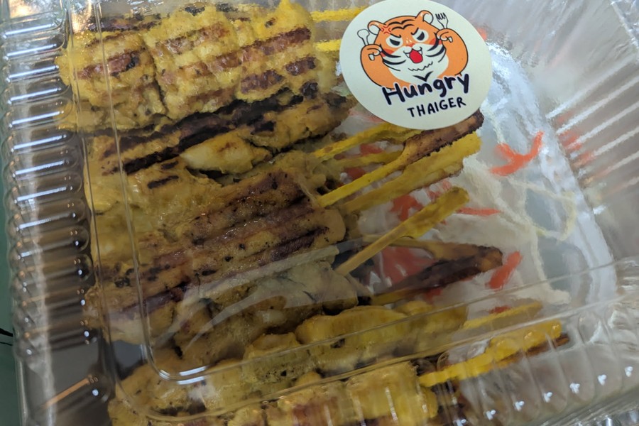 Hungry Thaiger 31 Thaiger grilled chicken skewers in a takeout container with a custom logo sticker printed at Little Rock Printing.
