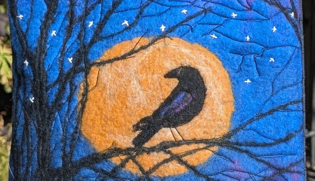 Felted raven artwork featuring a black bird silhouetted against an orange moon and blue night sky, printed at Little Rock Printing.